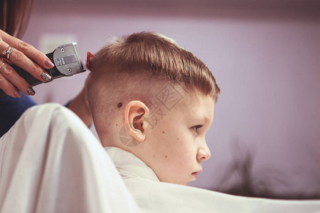 理发店的小男孩子害怕理发美发师的手给小男孩做发型图片