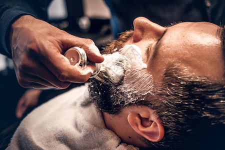 理发师将剃须泡沫应用到一个人图片