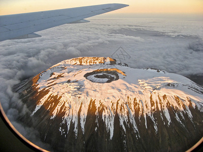 日出时飞过乞力马扎罗山显示全球变暖对雪覆图片