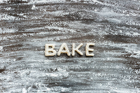 在木质表面用粉制成的饼干面团制成的文字烘烤的顶部视图图片