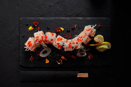 在石板和筷子上放着虾鲑鱼和鳄梨的mamenori美味卷的顶部视图图片