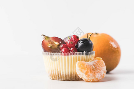 近距离观看带有浆果水果和橘子的甜纸杯蛋糕图片