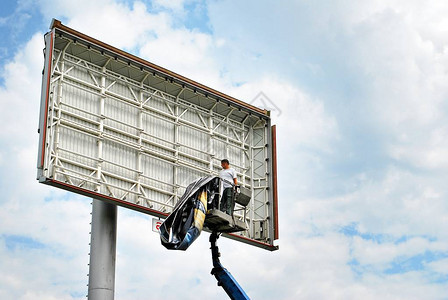 电动升降机上的工人安装广告牌图片