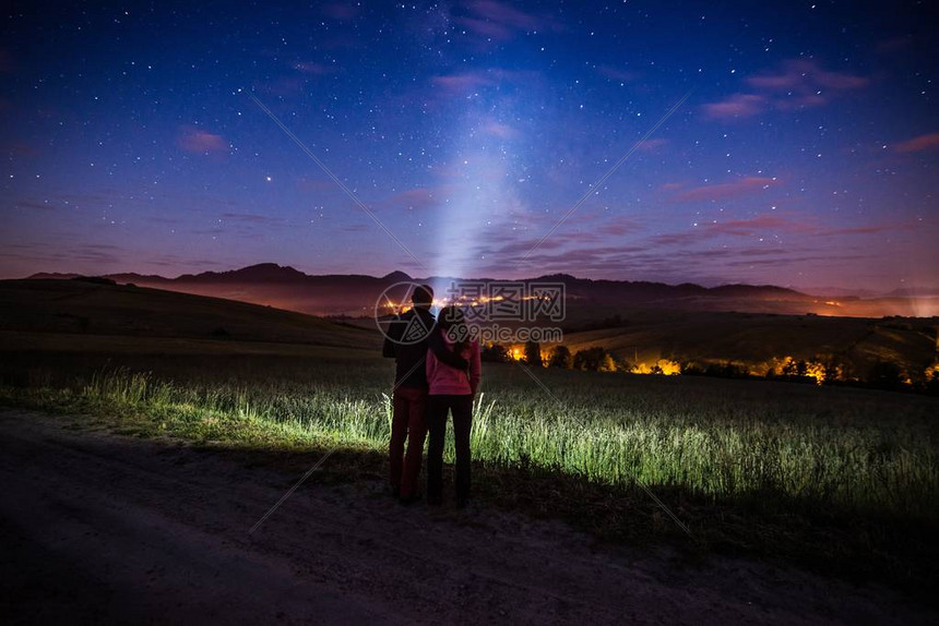 年轻快乐的情侣拥抱在山上星光之夜图片
