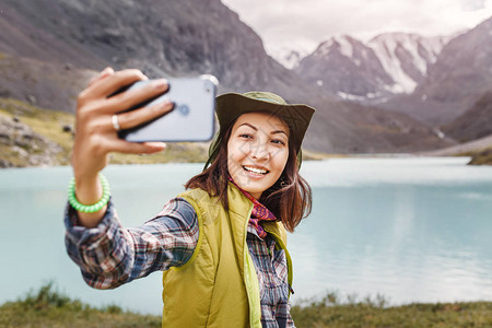 戴帽子的旅游女客与她的智能手机在阿尔泰美丽图片