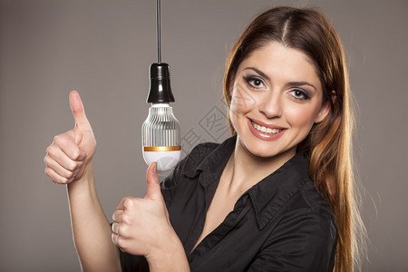 快乐的年轻女士在LED灯泡背景图片