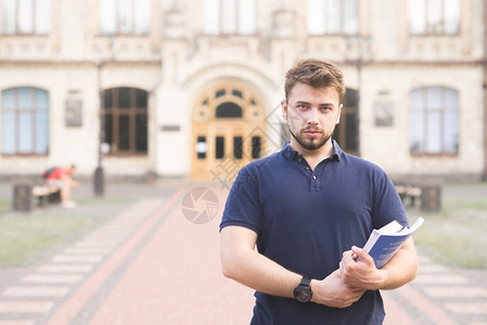 一个严肃的学生站在大学楼的手中图片