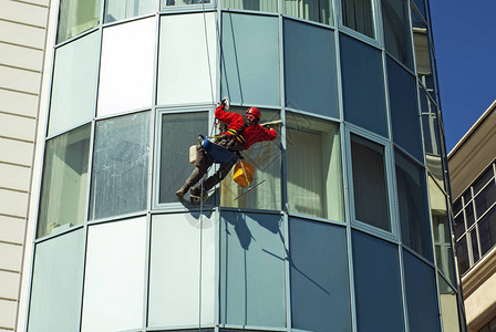 工人戴头盔从外面清洗高楼大的窗户图片