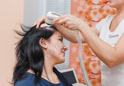 在美容诊所对女患者的头皮和毛囊进行毛发学和皮肤病学检查图片