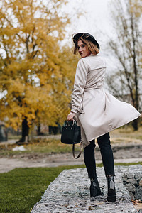 穿着海沟大衣和帽子的时髦女人在秋天公图片
