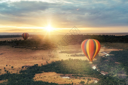 日出时漂浮在MasaiMara保留地上空的多彩热气球的图片