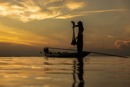 剪影渔夫与湖上落日的天空图片