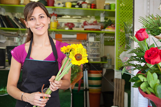 一位有吸引力的花店女老板在花店市场工作并制作新的插花图片