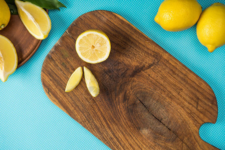 绿松石背景的木制切菜板上新鲜黄色柠檬的顶视图图片