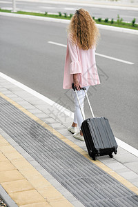 女人提着行李往车站走回头图片