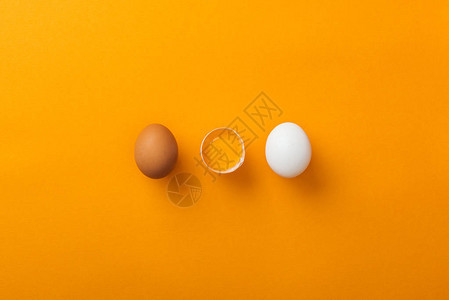 两只鸡蛋的顶部视图一颗在亮橙色图片