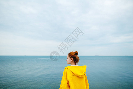 黄雨衣的红发女人背影看着蓝海的背图片