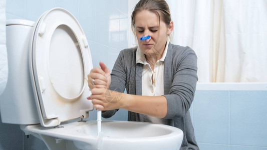 用衣服在鼻子上洗脏厕所的娇气女人图片