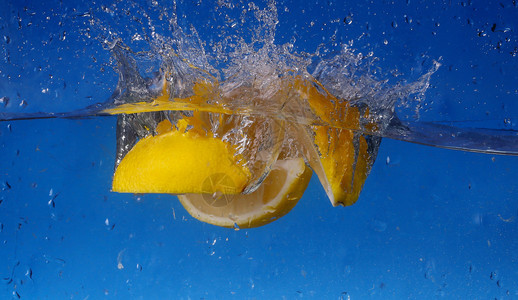 拼贴整个柠檬在渐变蓝色背景下掉入水中图片