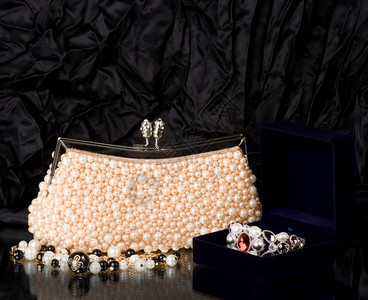 感时尚手提包与黑色背景上的珍珠首饰图片