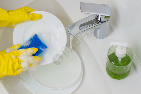 戴着黄色手套洗碗的过程图片