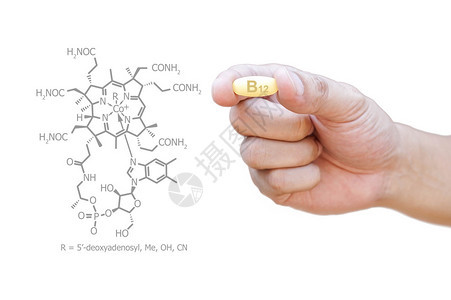 手拿着维生素B12丸与剪报图片