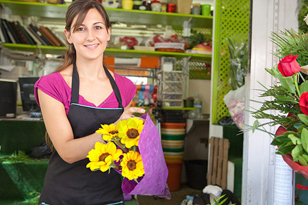 迷人的花店老板女人在她的花卉市场商店的柜台工作图片