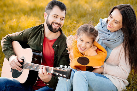 女儿在草地山上放轻松而父亲弹吉他时图片