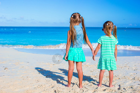 两姐妹在白色沙滩上看海的背影图片