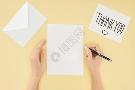 裁剪的人拿着笔空白纸带有感谢信的明信片和黄色背景中突显的sma背景图片