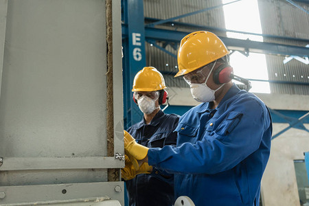 两名蓝领工人在隔绝工业压力容器时佩戴防护设备图片