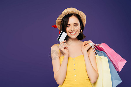 戴草帽微笑的女孩带着袋装着信用卡的购物袋图片