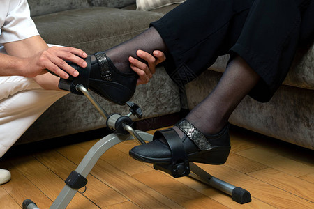 男治疗师在固定的康复踏板上协助高级妇女步行的情况有详细介图片