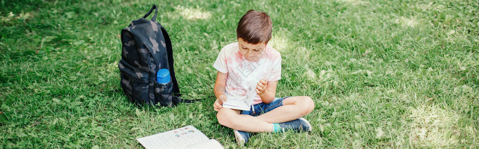 小学生坐在公园户外做功课孩子在外面看书自我教育学习儿童早期发育图片