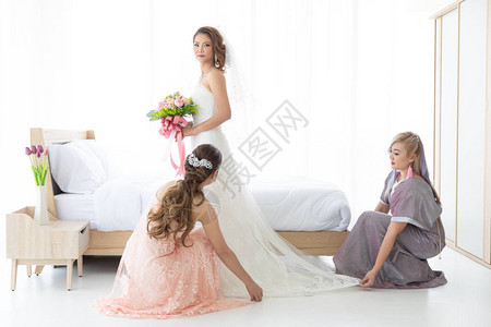 伴娘帮助新娘试婚纱和化妆服装快乐而有趣爱和朋图片