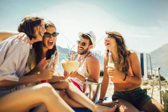 年轻朋友在阳光明媚的沙滩上聊的很开心图片