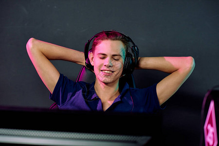 戴着耳机的年轻微笑放松的男视频游戏玩家在电子竞技游戏之间享受休息图片