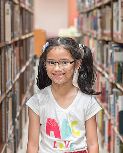 站在书架之间的学校图书馆的亚洲女孩子认为书籍资源图片