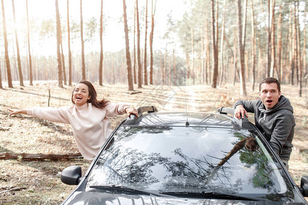 快乐的年轻男女从车窗里爬了出来在森林里开车旅行乡村旅图片