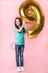 庆祝生日有9个气球的兴奋女孩在粉红图片