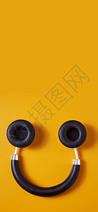 一对黑色无线全尺寸耳机倒置在橙色背景上图片