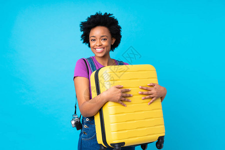 携带手提箱的非洲美旅行女士与孤立蓝背景的蓝色背景相隔千丝背景图片