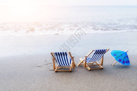 沙滩上的两把沙滩椅和一把小伞背景图片