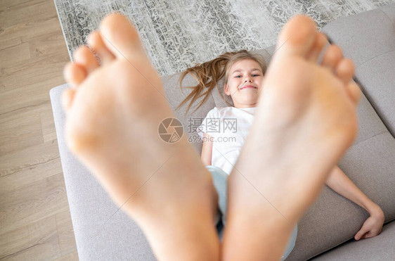 青春期前的女孩躺在沙发上赤脚高举起图片