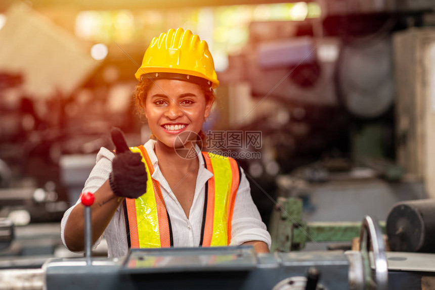 带着安全头盔的少女工人在工业厂用钢铁机做工图片