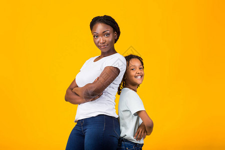 自信的女人黑妈和孩子背靠站着带着折臂在黄色图片