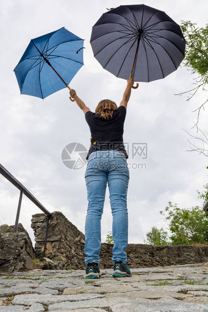 年轻女人在公园撑着两把雨伞图片