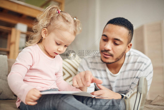 年轻呆在家里的爸和可爱的小女儿一起读书的画像图片