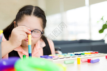 爱自闭症的可爱女孩通过将康复中心的彩色棒连接起来学习发展背景图片