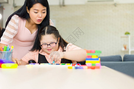 自闭症可爱女孩在家练习连接颜色棒图片